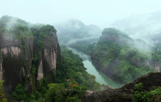 Mist-shrouded river valley of a majestic mountain range in China, depicted in the suspense novel Last Flower by Niklas Three