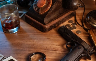 Iconic hard-boiled detective desk with a whiskey glass, phone, photos, money, and a pistol, evoking a classic mystery scene.